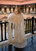 Full-length back view of a luxury champagne crystals wedding party dress, showing the dramatic flowing puddle train and the voluminous detachable ruffle tulle sleeves with cape extensions.