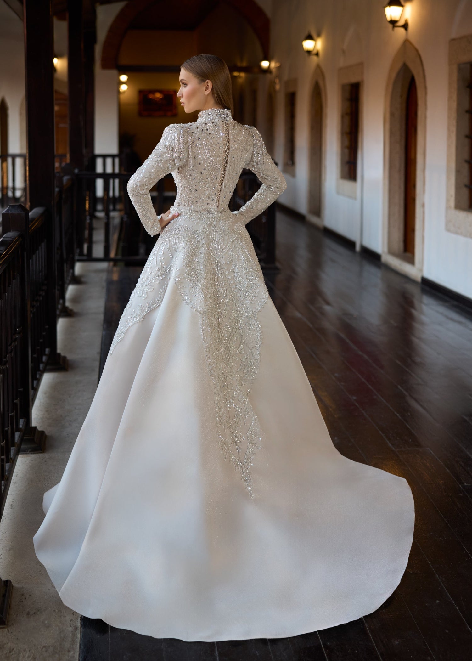 Full-length back view of the ivory haute couture modest wedding gown, showcasing the elegant button-up back closure and the crystal embroidery cascading down the sweeping detachable overskirt train.