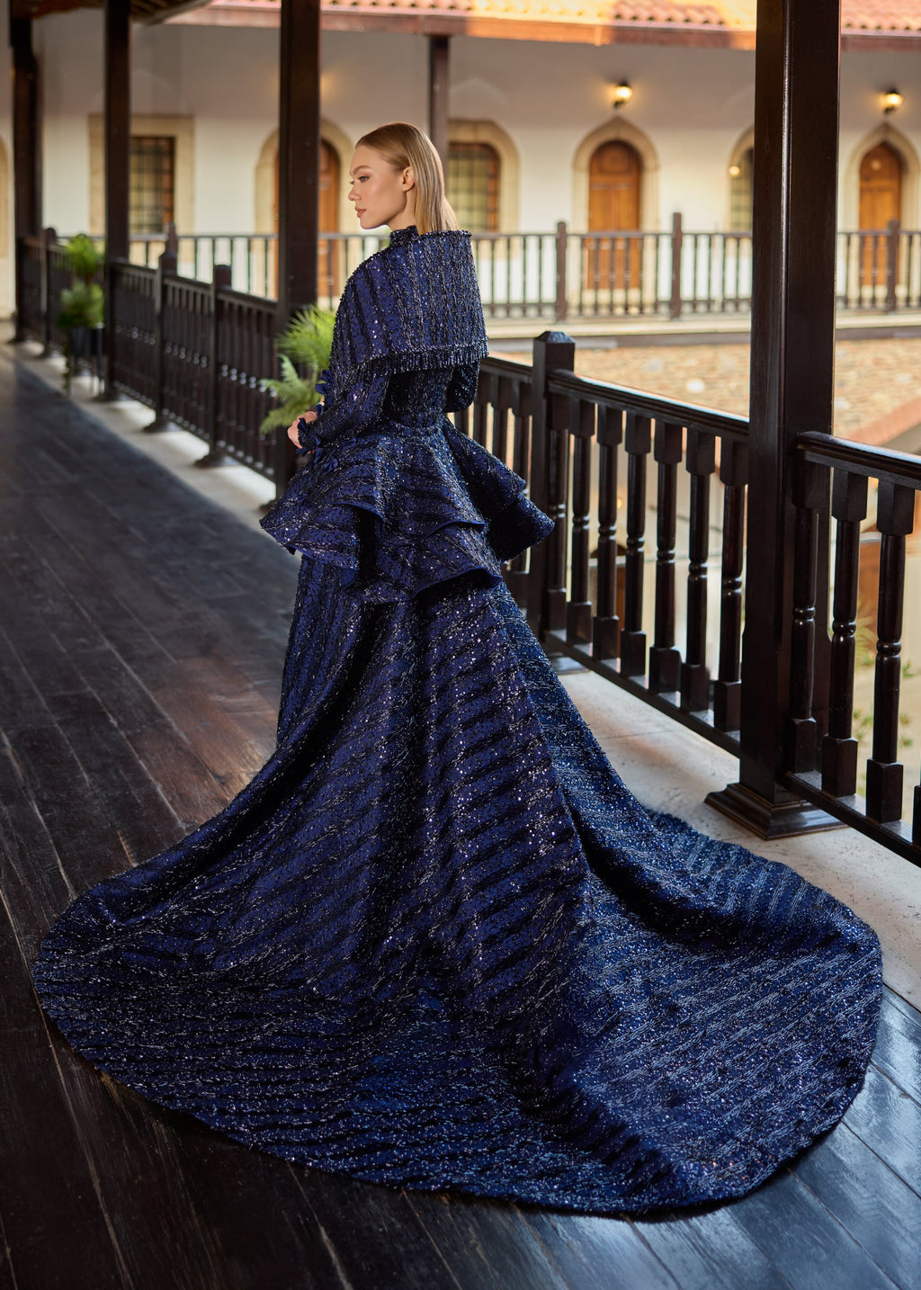 Full-length back view of the navy blue hand-beaded modest wedding gown, showcasing the grand cascading train of the detachable over-skirt and the beautifully matching draped sequin shawl.