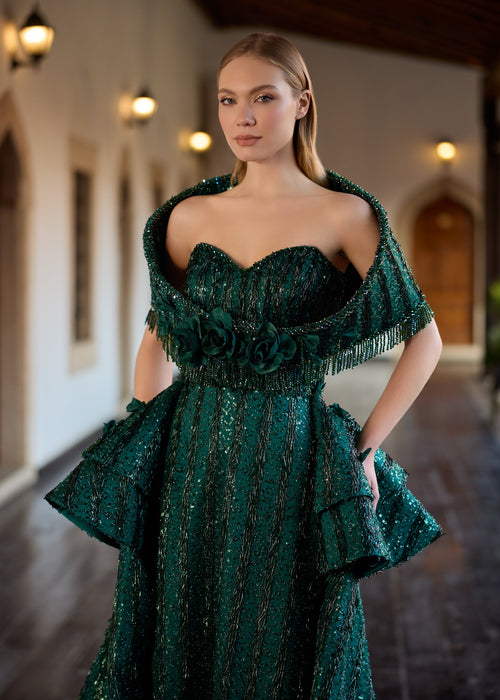 Close-up of the sweetheart corset bodice, highlighting the detailed detachable fringed shoulder shawl and the row of handcrafted 3D emerald fabric roses at the waist.