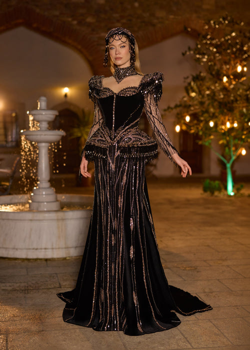 Full-length front view of the luxury black velvet henna dress showcasing the beautiful choker neck, keyhole chest cutout, structured fringe peplum hips, and copper embroidery.