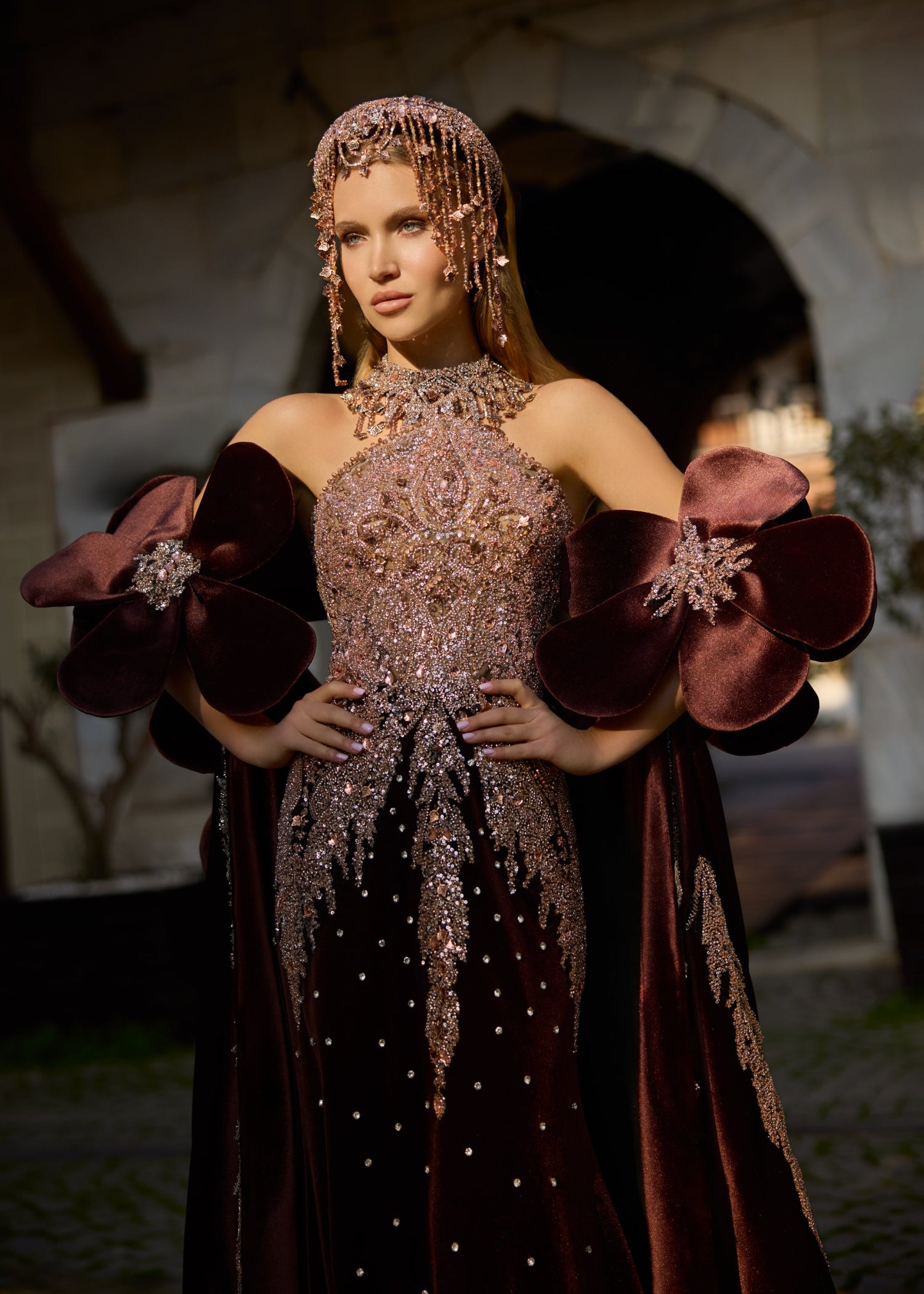 Full-length front view of a majestic deep burgundy velvet bridal kaftan gown with a sparkling hand-beaded corset, dramatic 3D floral arm accents, and a sweeping satin train.