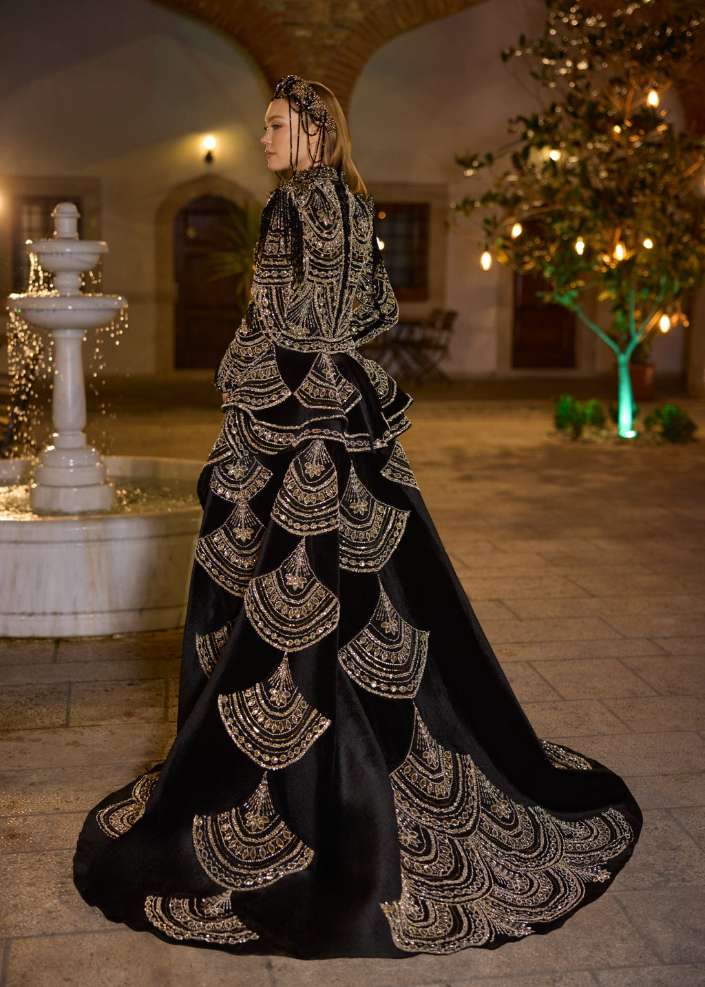 Full-length rear view showing the dramatic sweeping imperial train of the detachable velvet overskirt, intricately decorated with repeating gold hand-beaded scallop embroidery by Sultan Dress.