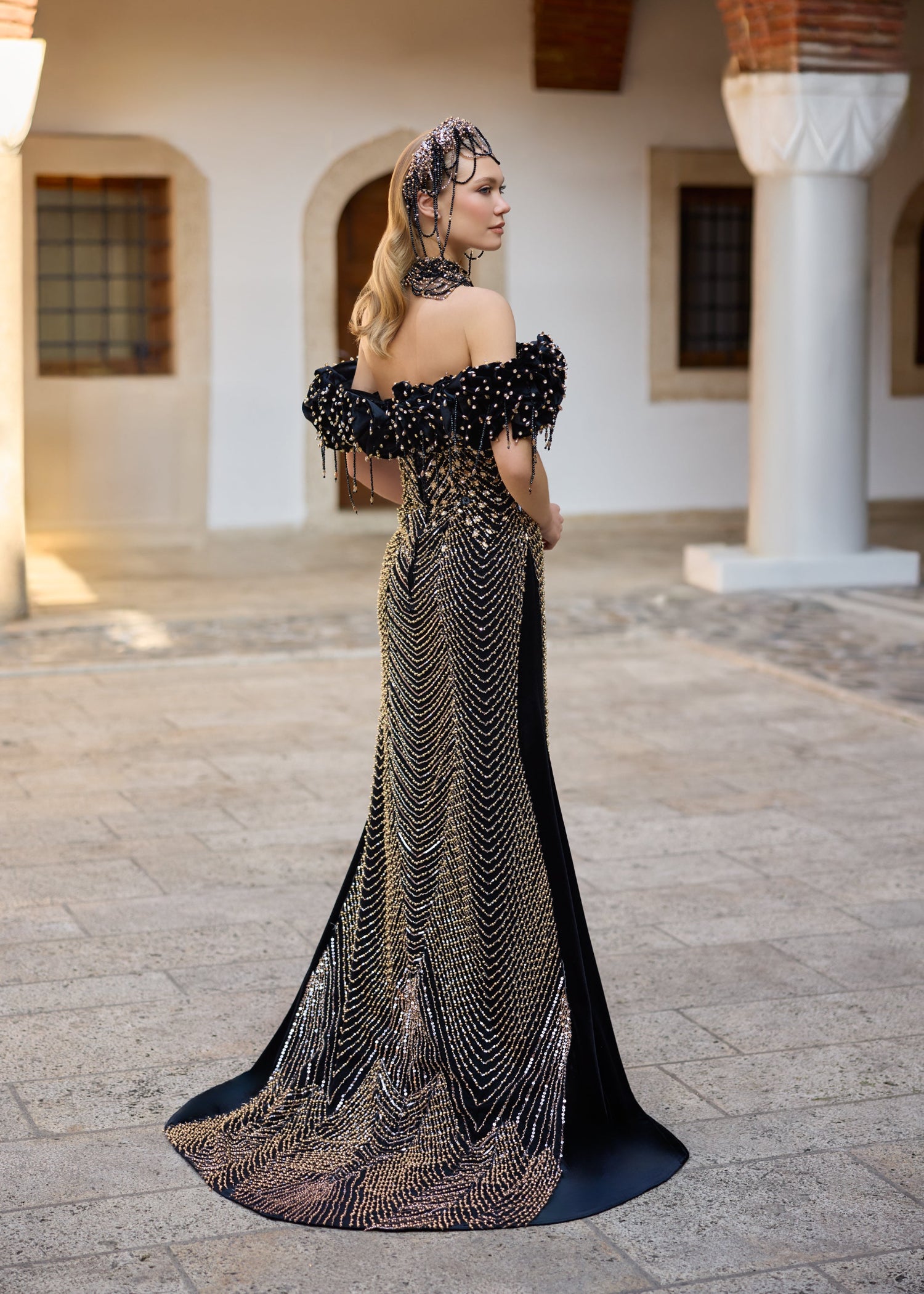 Back view of a black velvet mermaid henna dress featuring detachable overskirt, medium-length train, and handmade beadwork details.