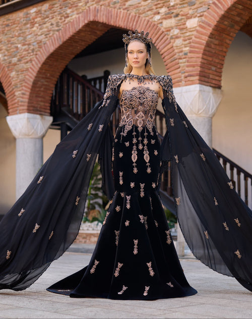 Black velvet mermaid henna dress featuring handmade beadwork, floor-length cape sleeves, and a matching crown.