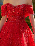Close-up view of the draped sweetheart bodice and sparkling red sequin tulle fabric on the formal evening dress.