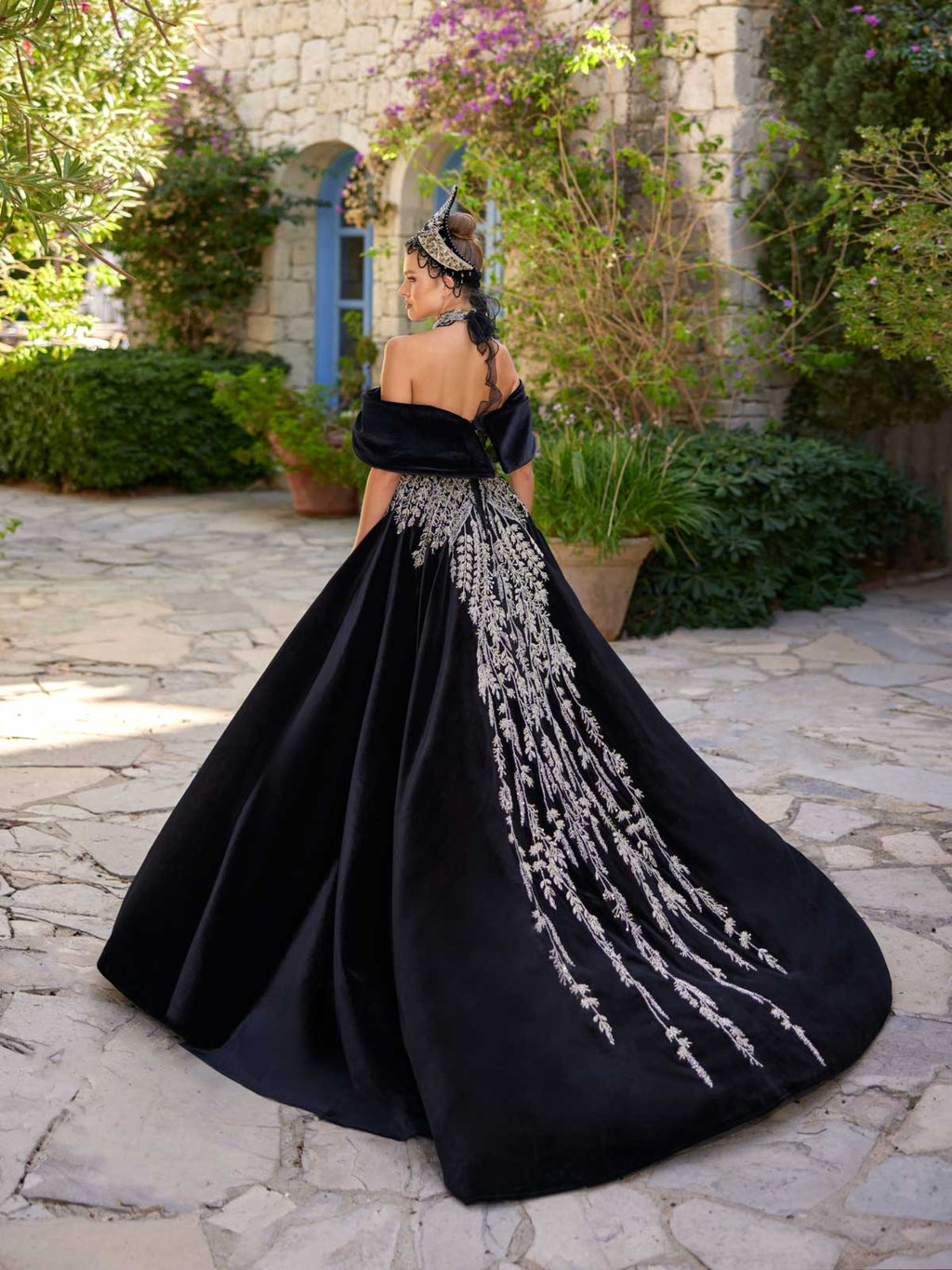 Rear view showing the sweeping black velvet A-line skirt with central silver crystal vine embroidery on the henna party gown by Sultan Dress.