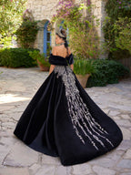 Rear view showing the sweeping black velvet A-line skirt with central silver crystal vine embroidery on the henna party gown by Sultan Dress.