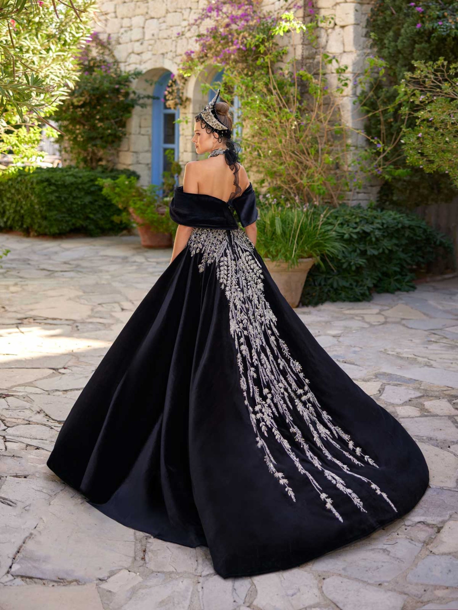 Rear view showing the sweeping black velvet A-line skirt with central silver crystal vine embroidery on the henna party gown by Sultan Dress.
