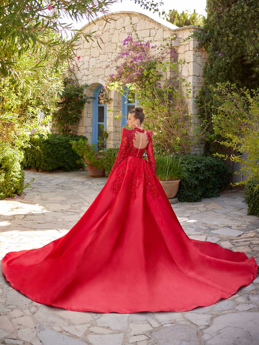 Rear view showing the dramatic detachable red satin overskirt train and illusion open back on the red beaded mermaid dress.