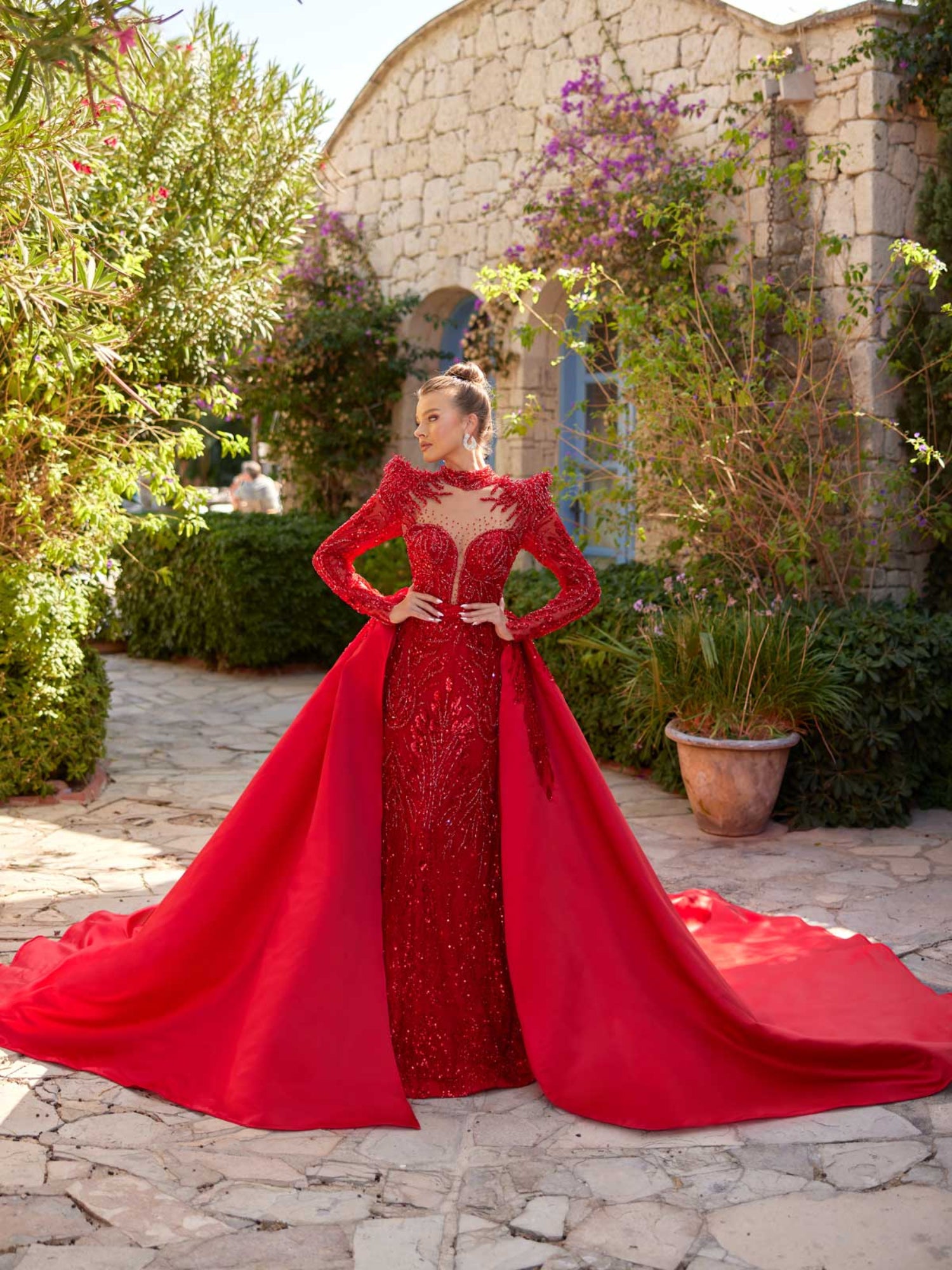 Full-length front view of the red sequin fitted mermaid gown styled with its sweeping detachable satin overskirt.