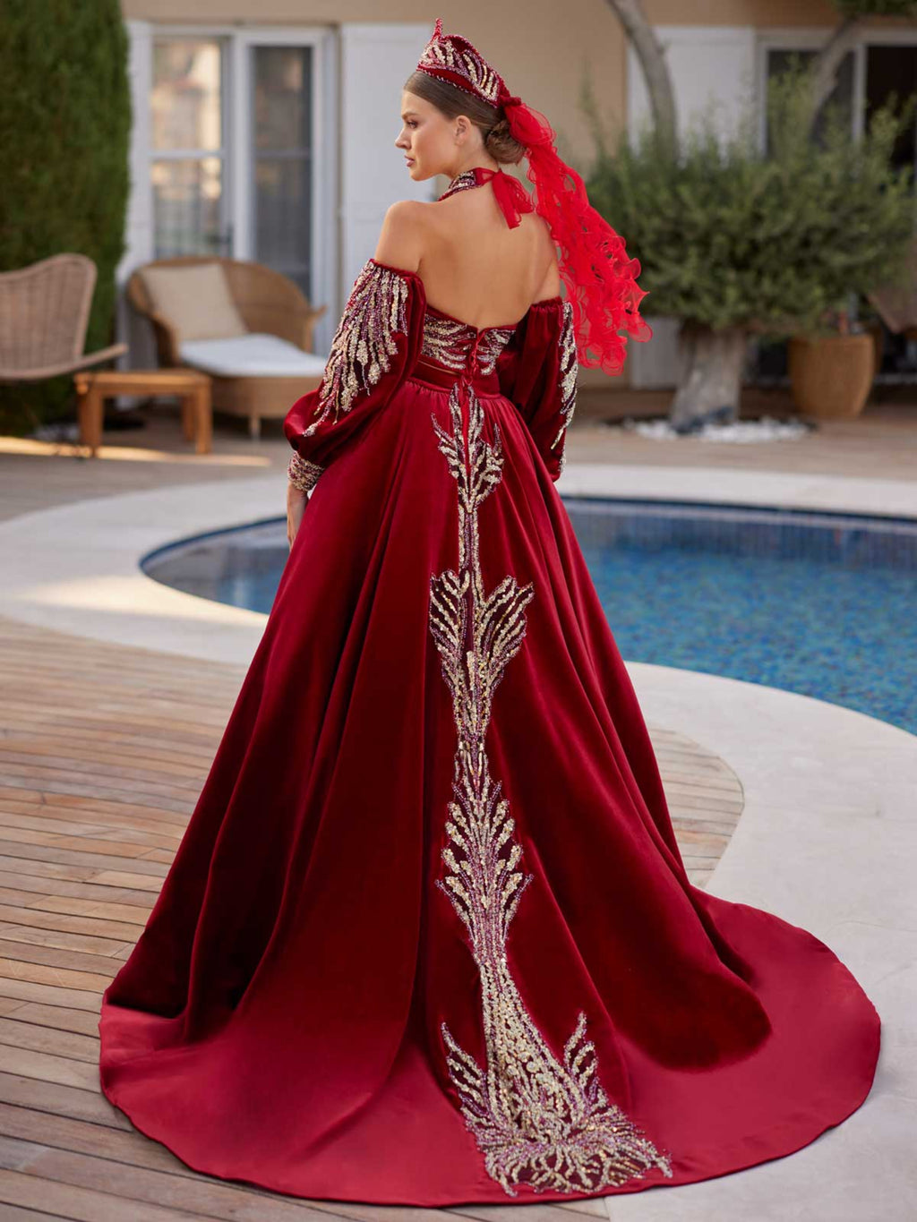 Rear view showing the sweeping red velvet train with central gold glitter leaf embroidery on the henna gown by Sultan Dress