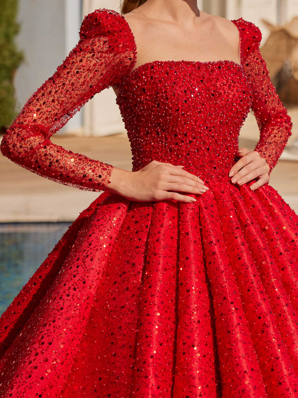 Close-up of the square neckline, puffed sleeve shoulders, and red sequin embroidery on the formal ball gown bodice.
