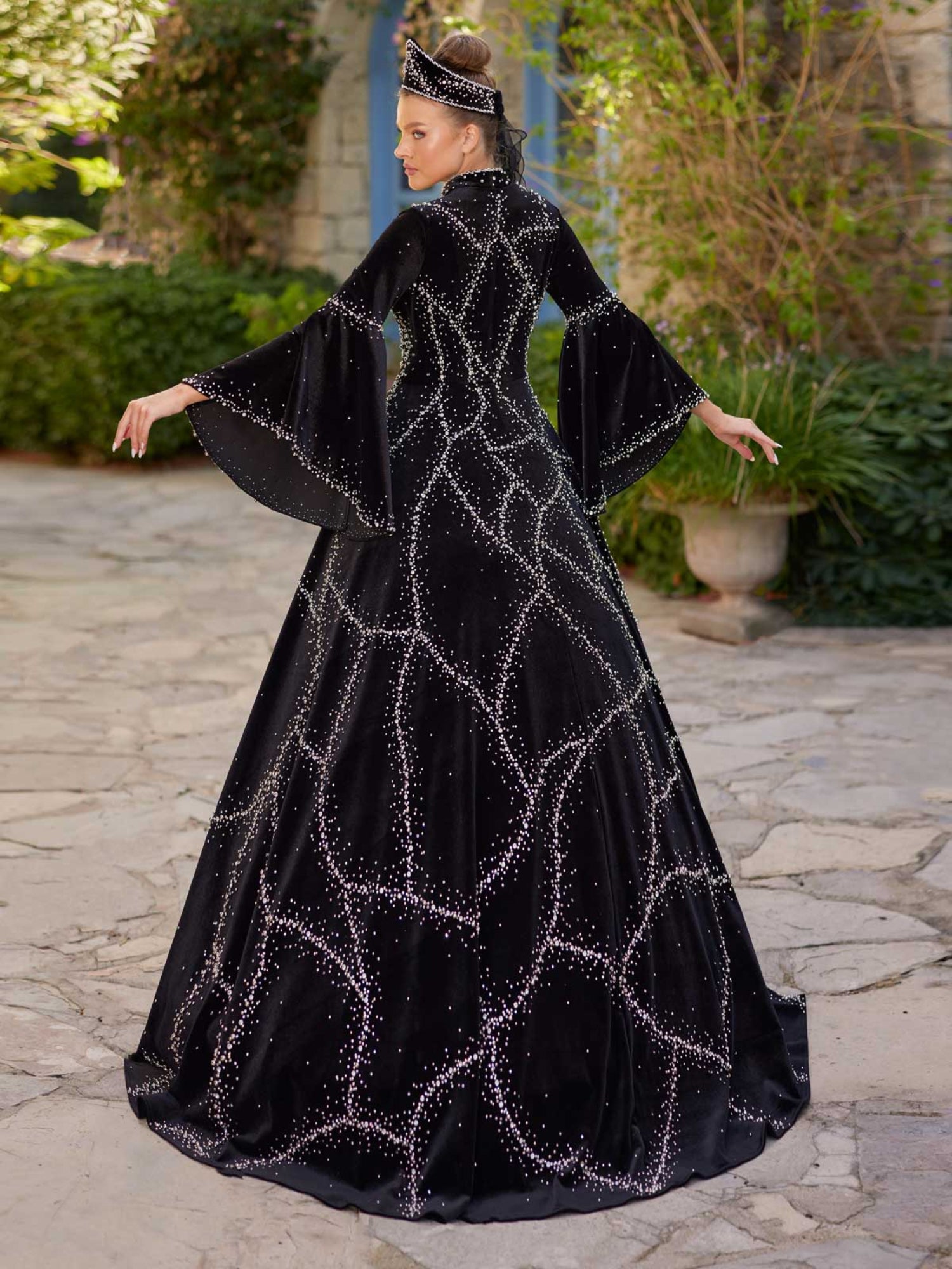 Rear view showing the high collar, beaded velvet lattice pattern, and flared bell sleeves on the black henna kaftan gown.