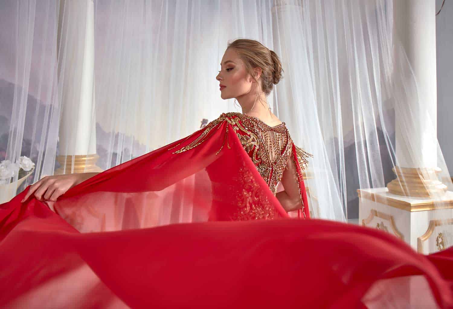 Full-length rear view showing the smooth drape and floor-length train of the red V-neck evening caftan dress.