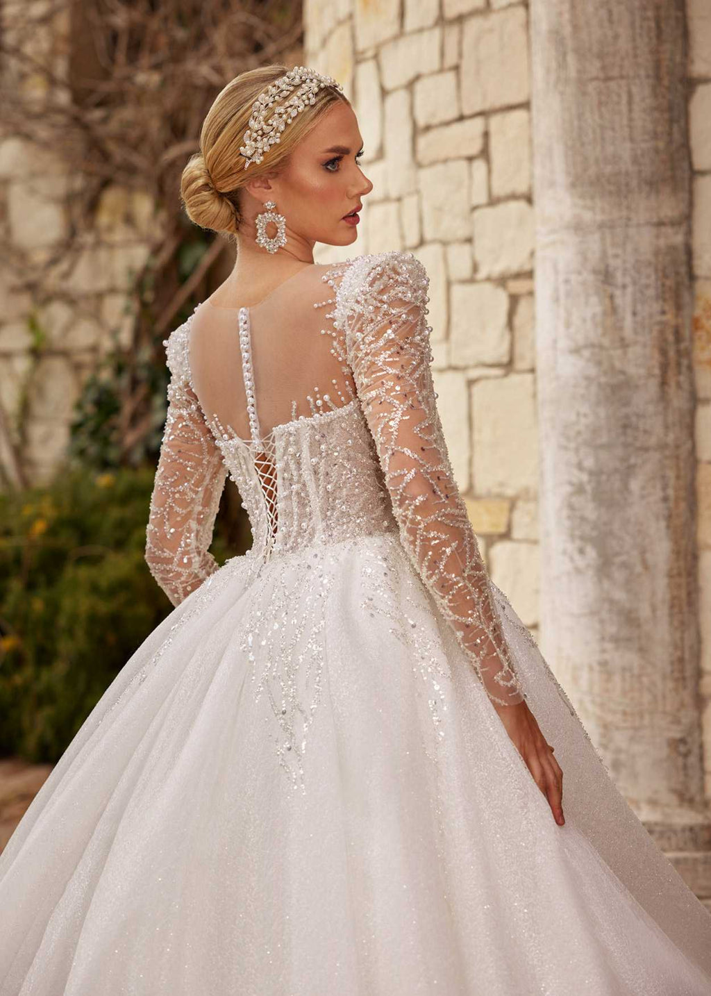 Rear view showing the illusion buttoned back, beaded long sleeves, and sparkling A-line tulle train.