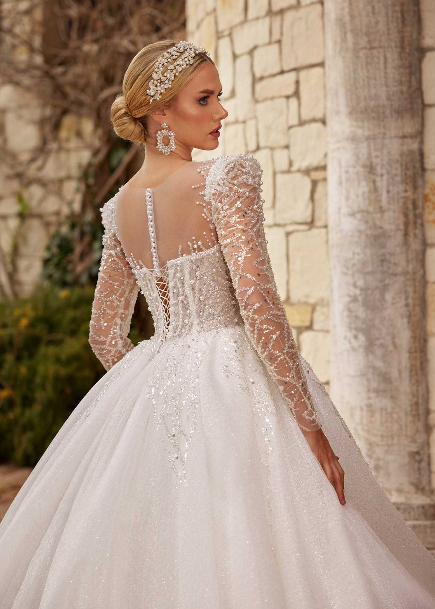 Rear view showing the illusion buttoned back, beaded long sleeves, and sparkling A-line tulle train.