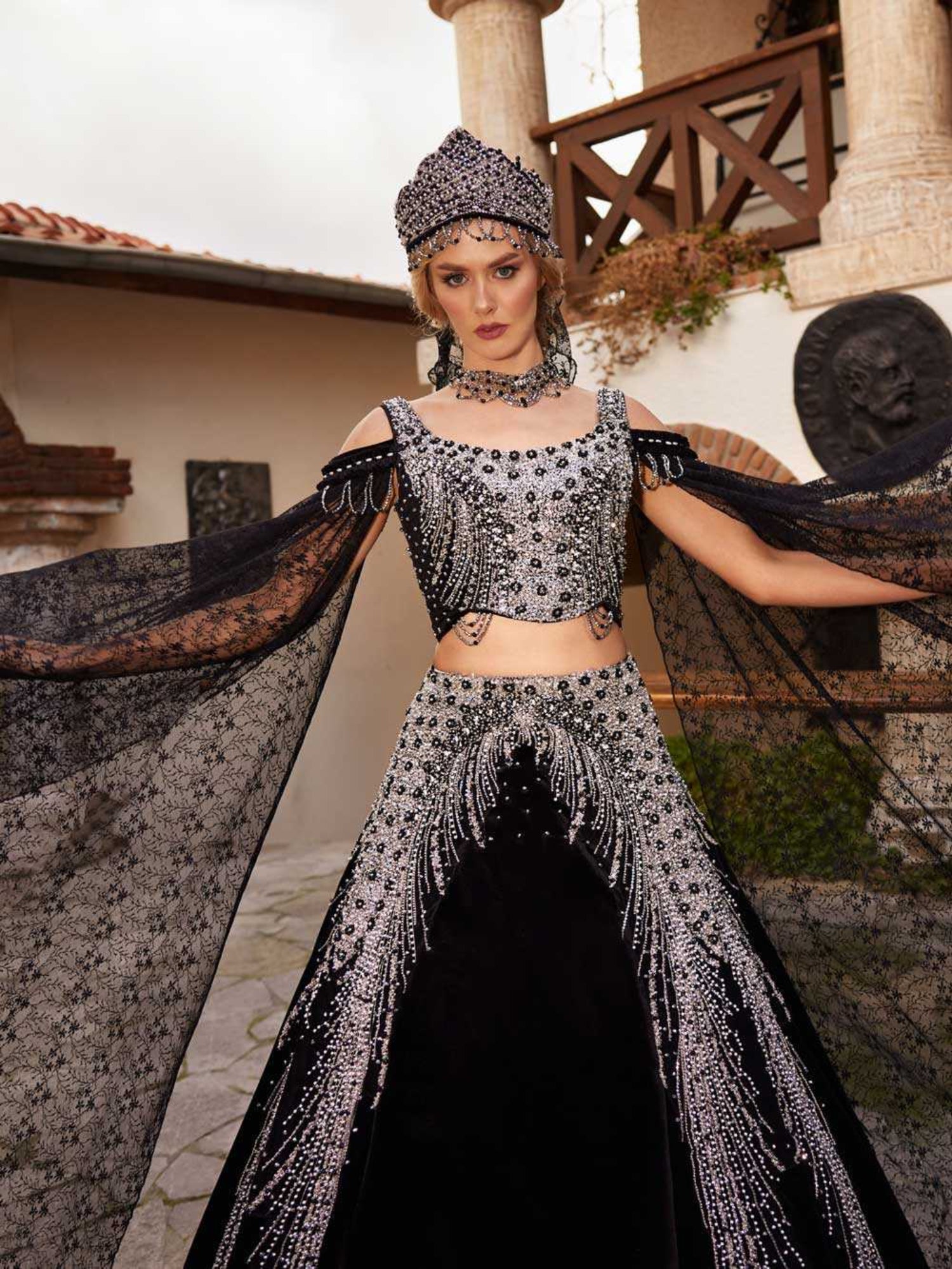 Close-up of the handcrafted silver crystal beadwork, cold-shoulder neckline, and draped lace sleeve on the black velvet top.