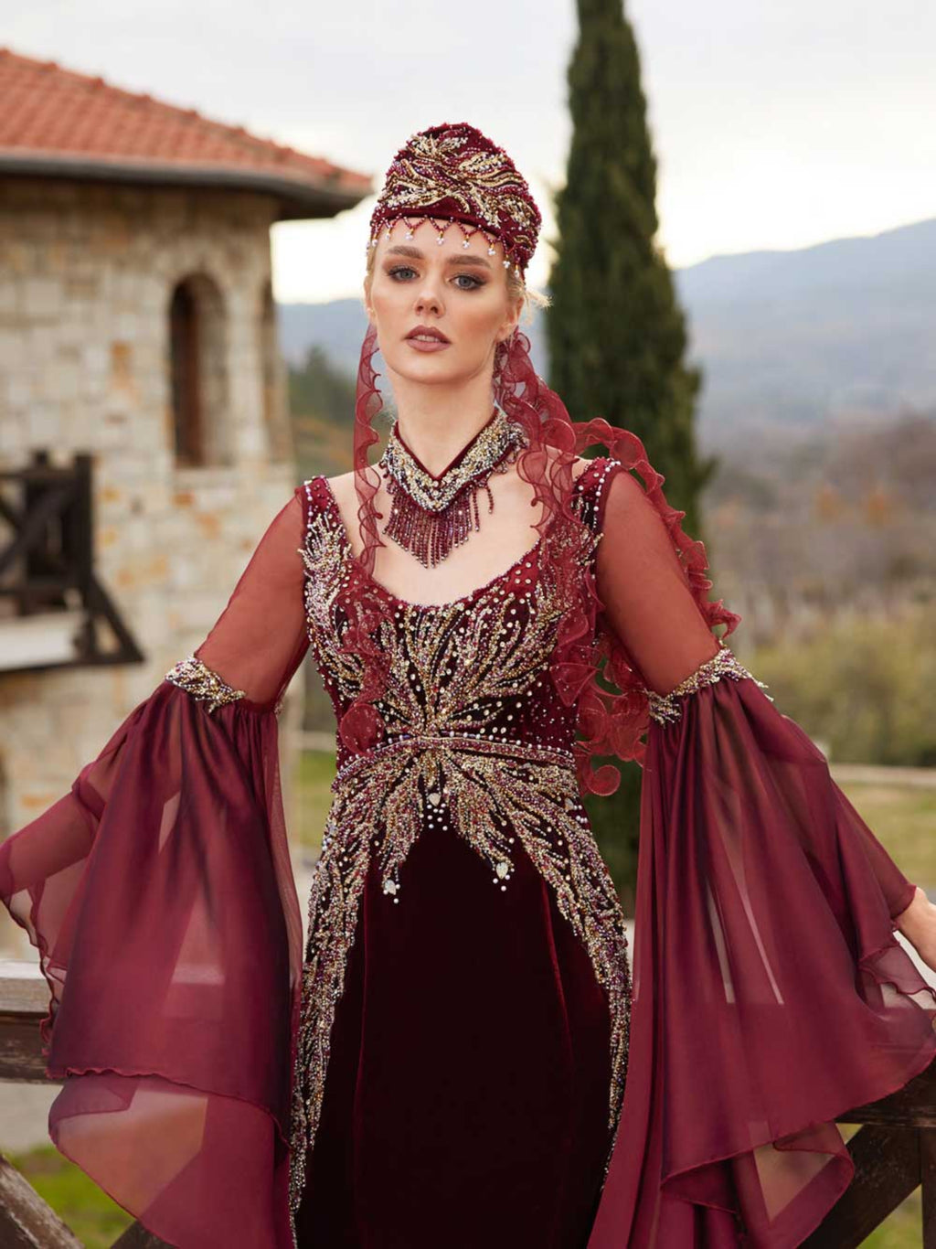 Close-up of the handcrafted gold lace, crystal beadwork, and neck collar accessory on the fitted burgundy velvet Henna gown.
