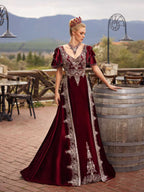Rear view showing the deep V-back, silver embroidery, and sweeping train on the burgundy velvet Turkish kaftan gown by Sultan Dress.