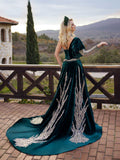 Rear view showing the cascading silver and gold sequin feather embroidery and sweeping train on the emerald green velvet one-shoulder gown by Sultan Dress.