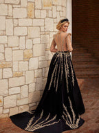 Rear view showing the sheer beaded illusion back and sweeping gold leaf embroidered train on the black velvet formal gown.