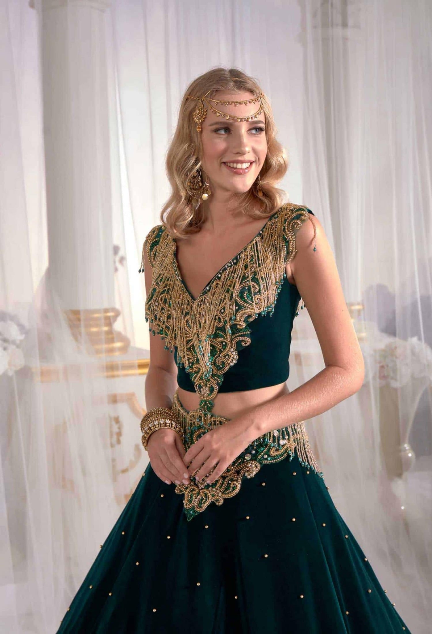Close-up detail view of the artisan handwork gold sequins and metallic thread embroidery on the dark green V-neck caftan.