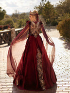 Rear view showcasing the colorful crystal beaded butterfly wing back embroidery and floor-length tulle cape sleeves on the maroon velvet Henna dress by Sultan Dress.