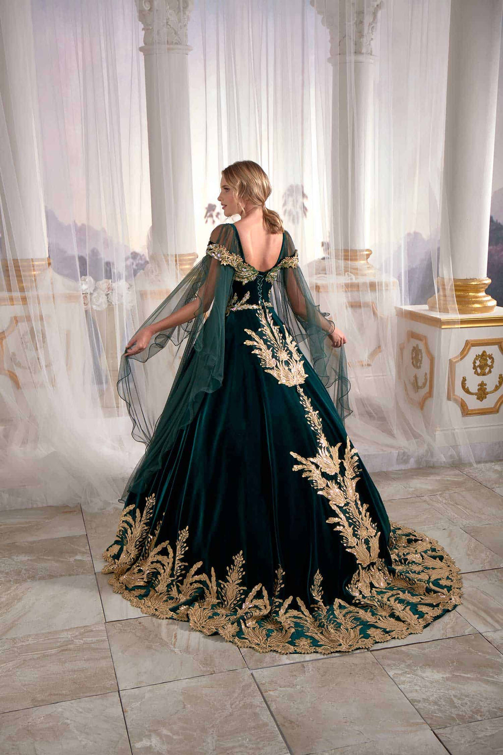 Rear profile showing the sweeping train and flowing velvet-bordered tulle veil of the emerald green evening caftan.
