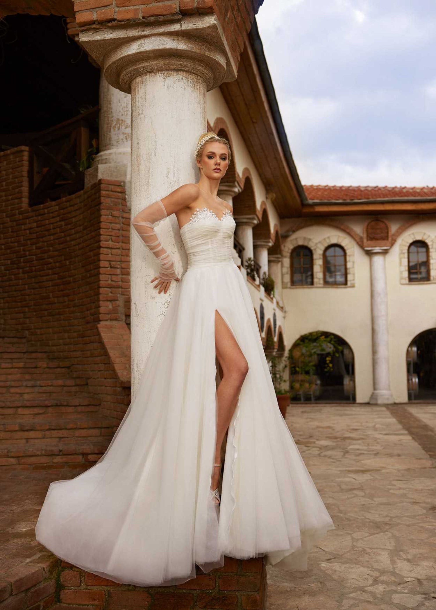 Side profile view highlighting the dramatic high leg slit and airy tulle skirt movement of style 1206.