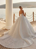 Rear view showcasing the grand cathedral train and heavy pearl embellishments on the strapless bridal gown.
