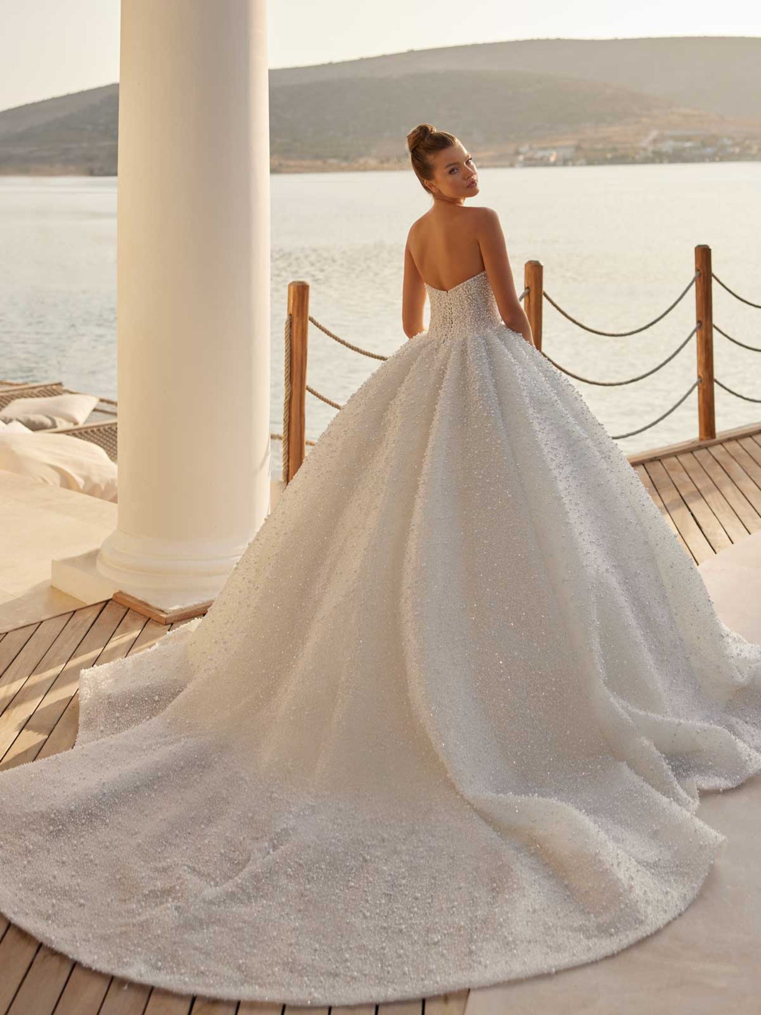 Rear view showcasing the grand cathedral train and heavy pearl embellishments on the strapless bridal gown.