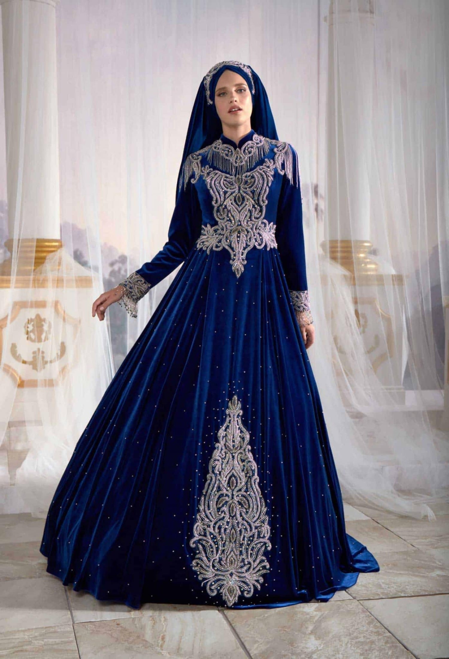 Full-length front profile of the dark blue long sleeve velvet hijab Muslim evening Ottoman caftan dress with hand-beaded embroidery by Sultan Dress.