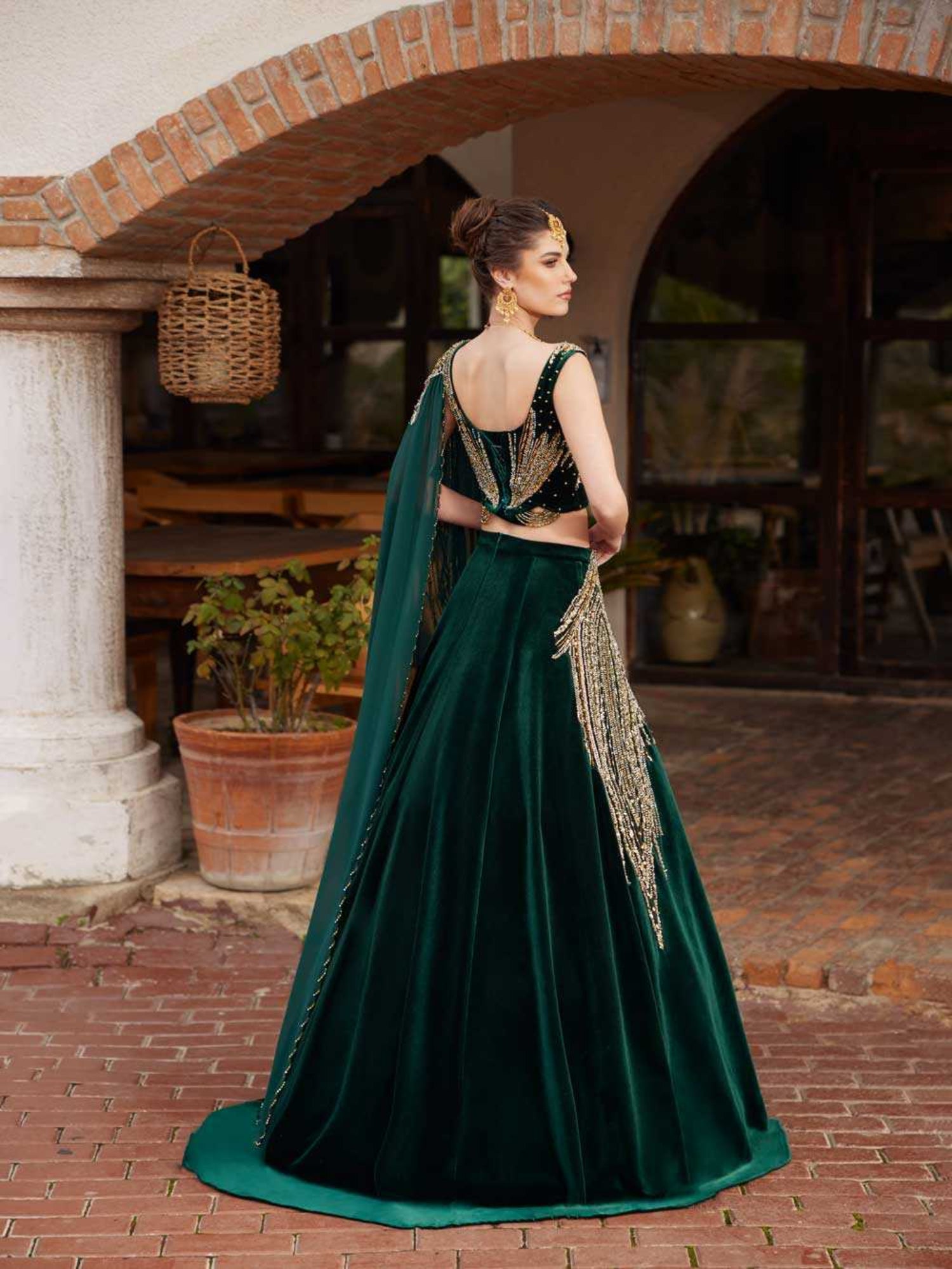 Rear view showing the fitted embroidered velvet blouse back and flared emerald green velvet skirt on the Mehndi dress by Sultan Dress.