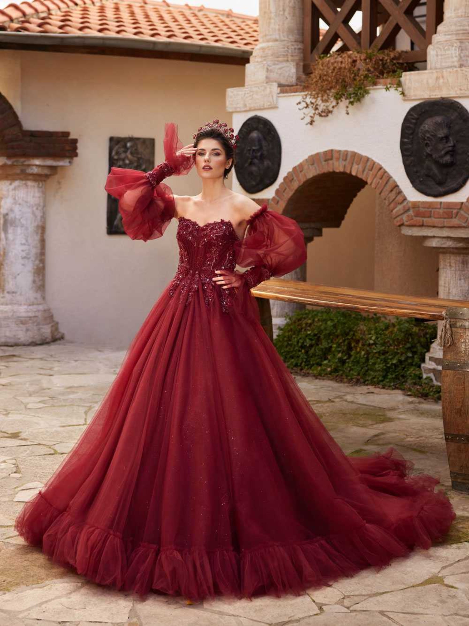 Full-length front view showing the maroon tulle ball gown with a sequin embellished sweetheart bodice and sheer off-the-shoulder puff sleeves by Sultan Dress.