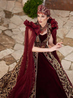 Front view of the maroon velvet Turkish Henna kaftan gown with all-over gold sequin lace embroidery, sweetheart neck, and mesh cape sleeves by Sultan Dress.