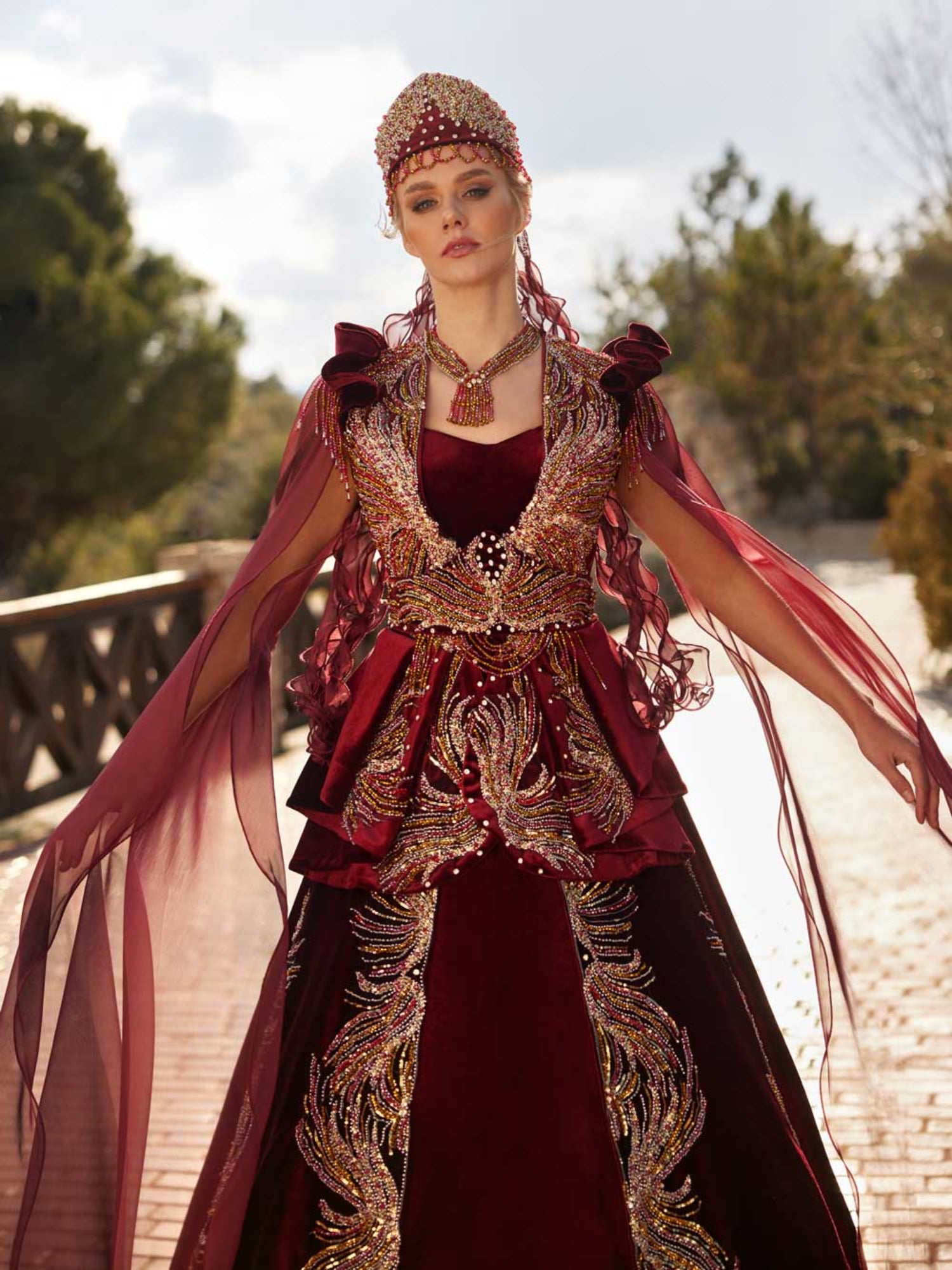 Front view of the maroon velvet Henna kaftan gown featuring gold embroidery, sweetheart neckline, beaded high neck collar, and crown headpiece.