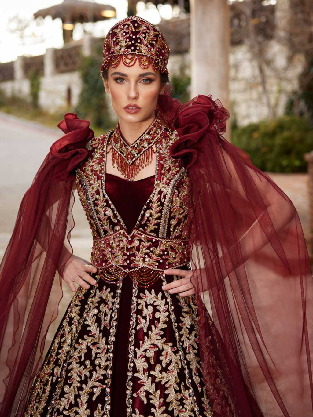 Close-up of the handcrafted gold sequin leaf lace, sweetheart neckline, and beaded collar on the maroon velvet kaftan gown.