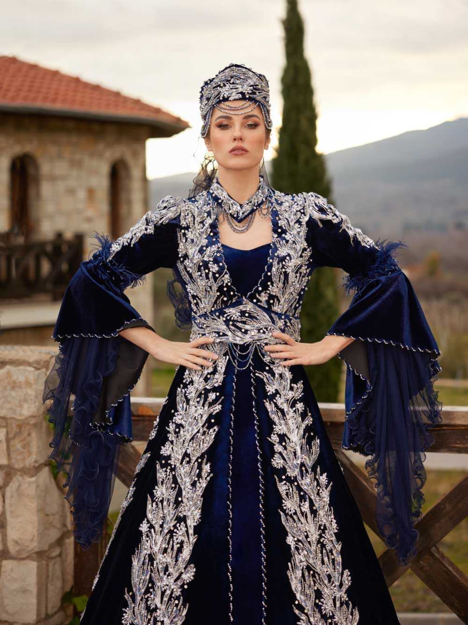 Close-up of the handcrafted silver sequin leaf embroidery and feather-trimmed bell sleeve on the navy blue velvet caftan.