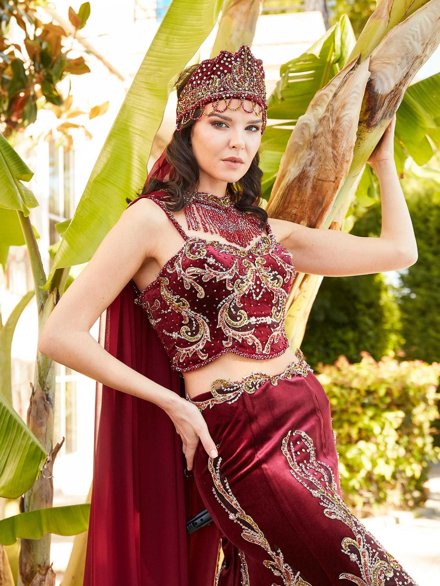 Rear profile displaying the flared mermaid skirt train and fitted waist of the red lehenga gown.