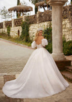 Rear view showing the lace-up corset back, dramatic ruffled sleeves, and sparkling tulle train of the ball gown.
