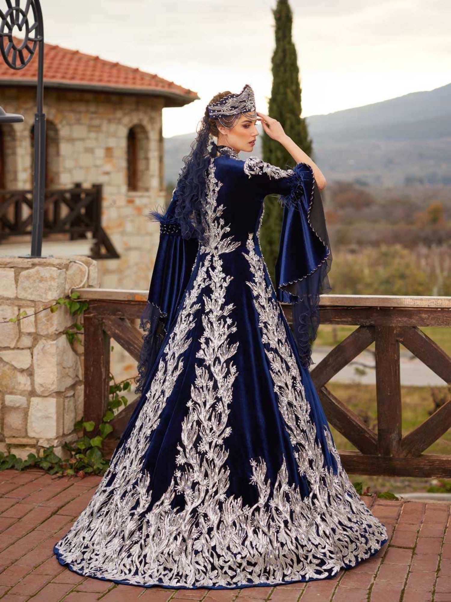 Rear view showing the rich silver embroidered back detail and sweeping A-line velvet skirt on the navy blue caftan gown.
