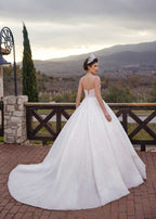 Rear view showing the open V-back corset lace-up and sweeping glitter cathedral train of the sunburst beaded ball gown.
