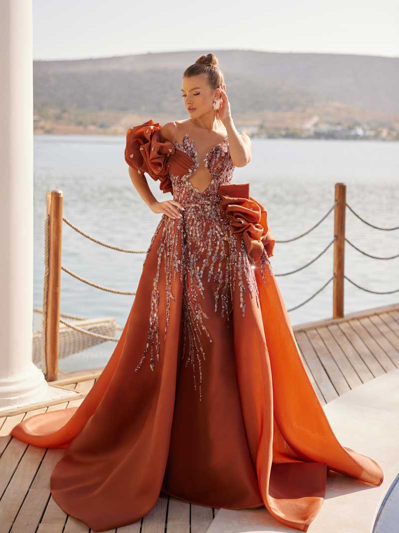 Front view of the terracotta copper sparkly sequin prom ball gown featuring sculptural organza rose accents and detachable overskirt train by Sultan Dress.