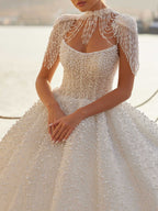 Bridal gown styled with a detachable high-neck pearl fringe shoulder capelet collar over the strapless pearl-beaded bodice.